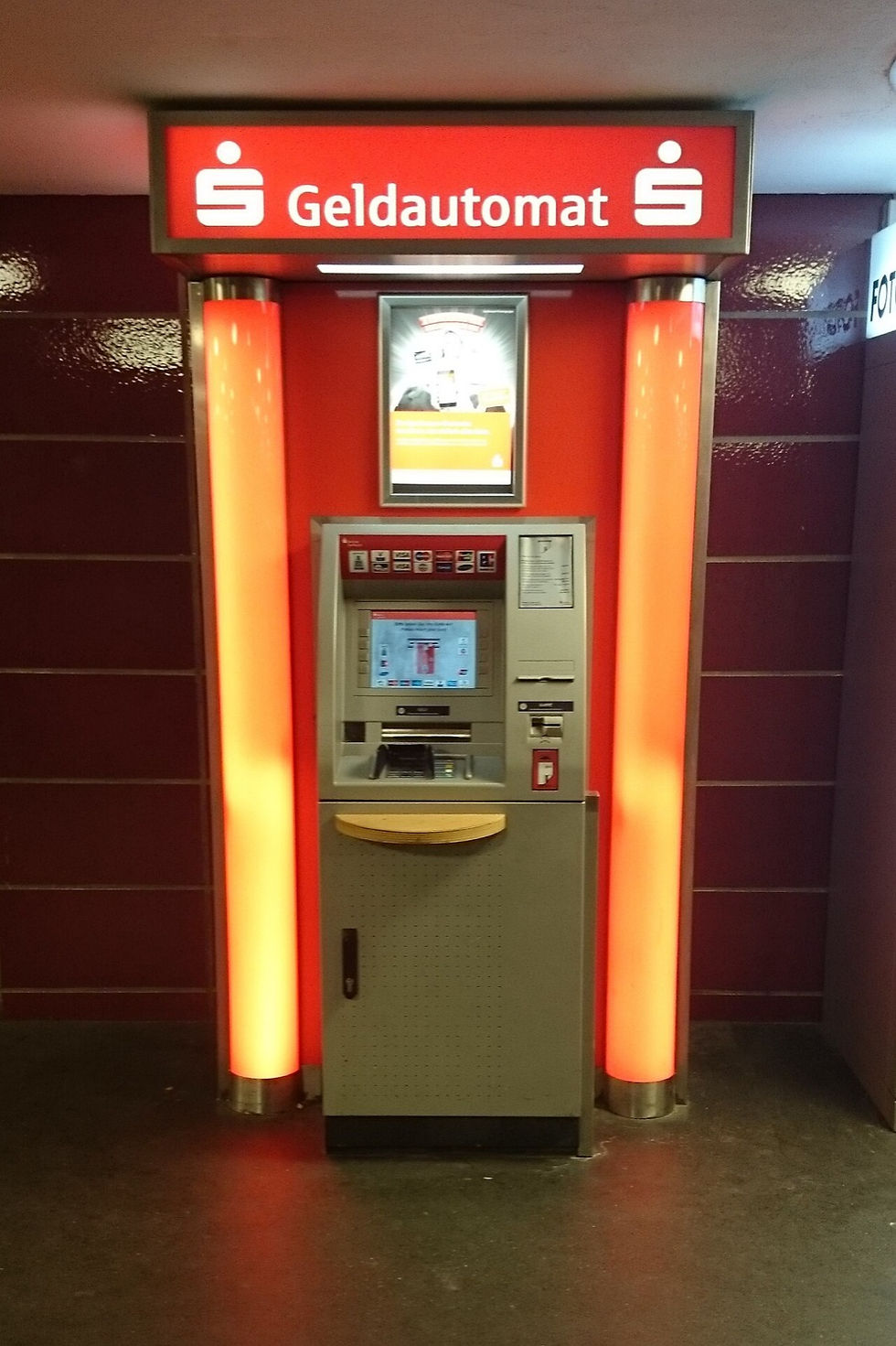 A Sparkasse bank cash machine, a Geldautomat, glowing between orange columns at Moeckernbruecke in Berlin