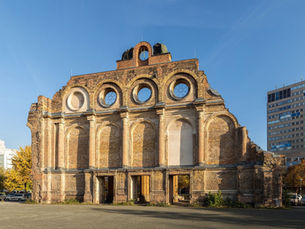 The rear of the ruined portico of the Anhalter Bahnhof in Berlin-Kreuzberg, its brick arches open to the sky with modern office towers behind
