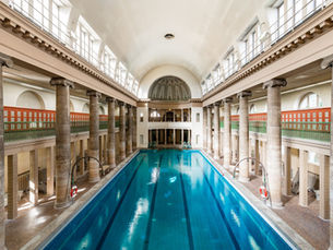 The colonnaded 1914 swimming hall of Stadtbad Neukölln, with turquoise water running between two rows of stone columns