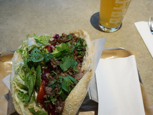 A Berlin-style döner with fresh salad and herbs, served with a small beer