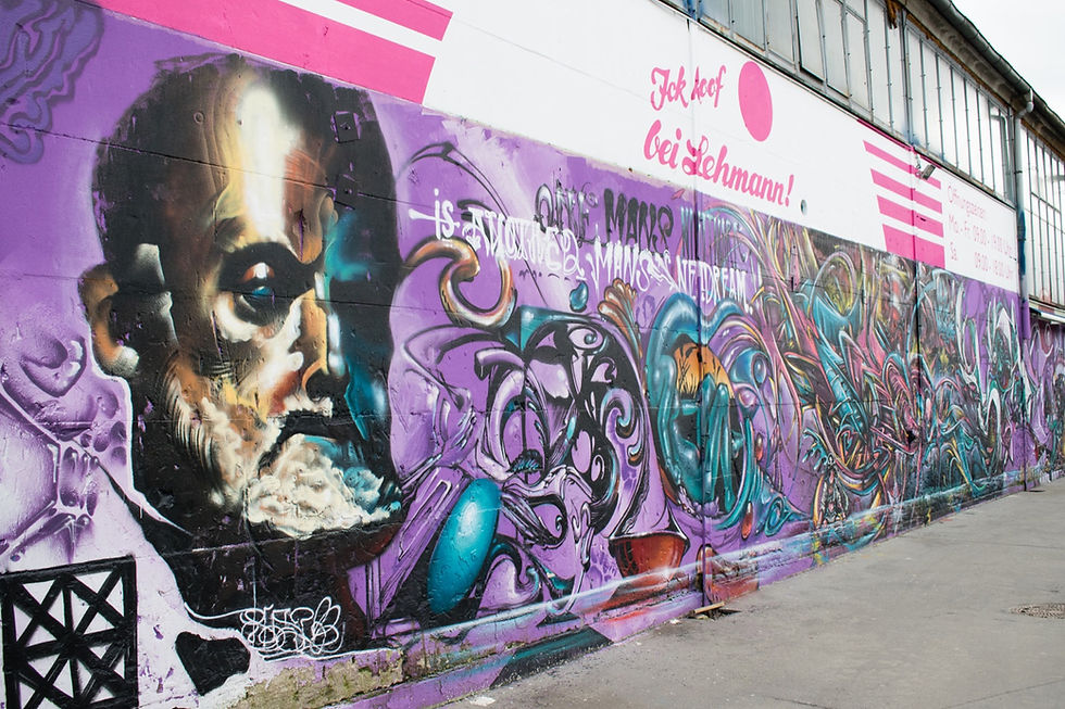 Colourful purple and pink graffiti and a large painted face mural on a wall at the RAW-Gelände former railway yard in Berlin-Friedrichshain