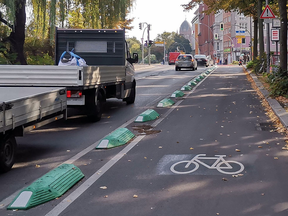 Protected Berlin bike lane with green separation kerbs, a bicycle road marking and city traffic beside it