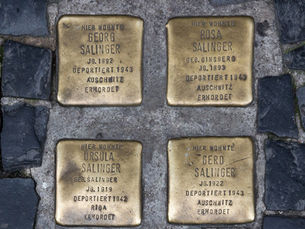 Four brass Stolpersteine for the Salinger family set into dark cobblestones in a Berlin pavement