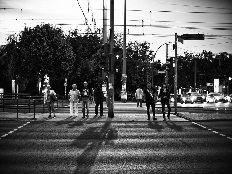 People standing on a Berlin pavement waiting to cross the road at a set of traffic lights