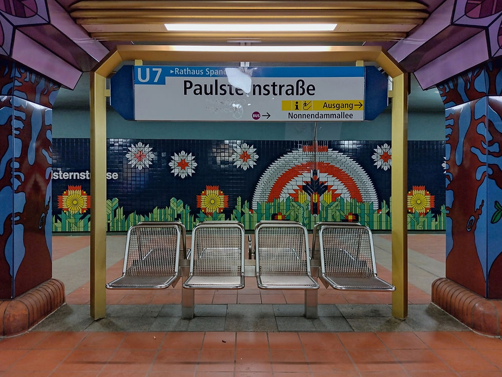 The tiled flower and rainbow mosaic on the platform wall at Paulsternstraße station