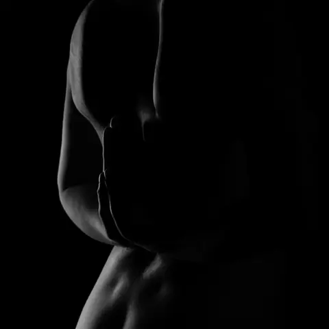 Schwarz-Weiß-Bild einer Frau in einer minimalistischen Pose, bei der Schatten und Licht perfekt harmonieren