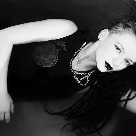 Schwarz-Weiß-Fotografie einer Frau mit Dreadlocks, die entspannt im Wasser liegt – künstlerischer Ausdruck mit Kontrastspiel.