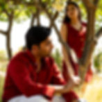 Model in red shirt from Assahi’s men’s collection, standing in lush outdoor setting