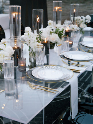 Modern wedding place setting with gold flatware, black charger, and tall glass candleholders styled by an Austin luxury wedding planner