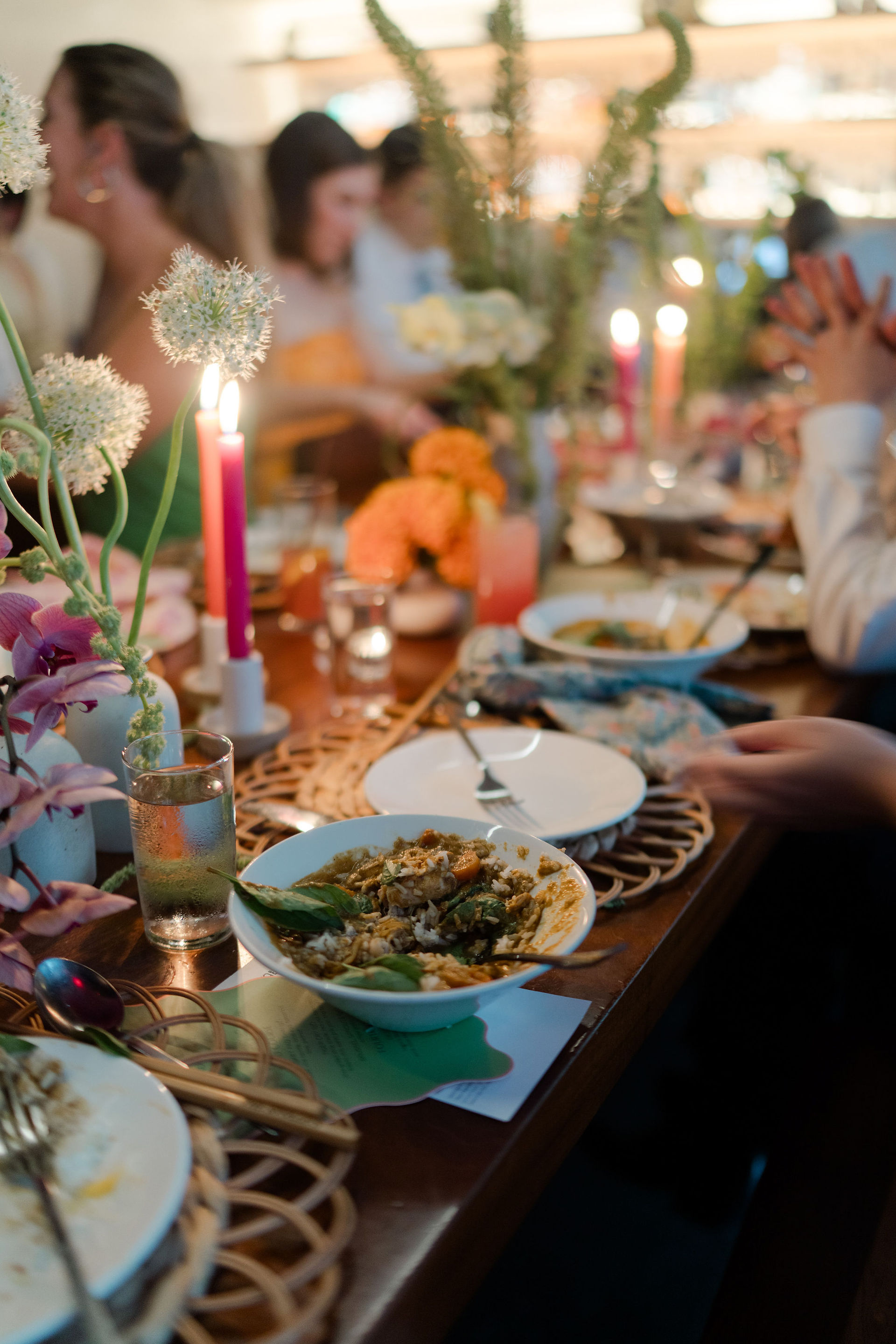 A candlelit wedding reception dinner with taper candles, floral, and hot food.