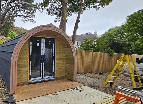 Circular wooden glamping pod with a small porch and decorative carvings nestled in trees