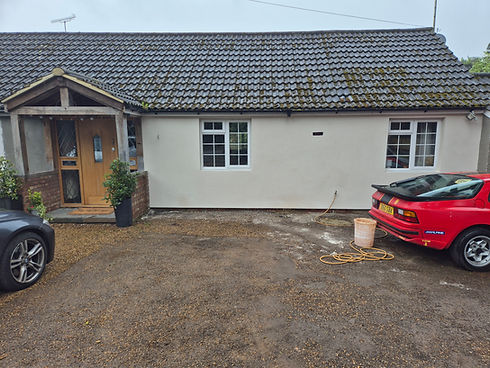Modern large two storey white rendered house with a grey tiled roof and matching paved driveway