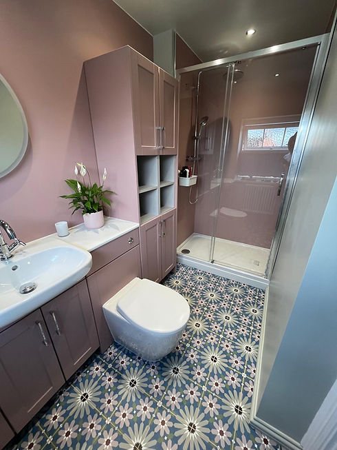 Compact bathroom layout with pink walls patterned tile flooring glass shower enclosure and vanity unit