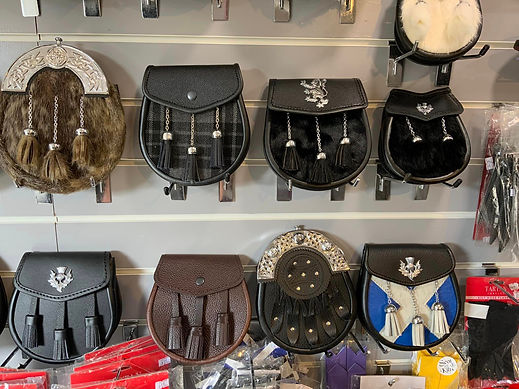 A retail wall display featuring a collection of various traditional Scottish leather and fur sporrans arranged in rows