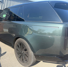Rear side view of a luxury dark green Range Rover SUV parked outdoors