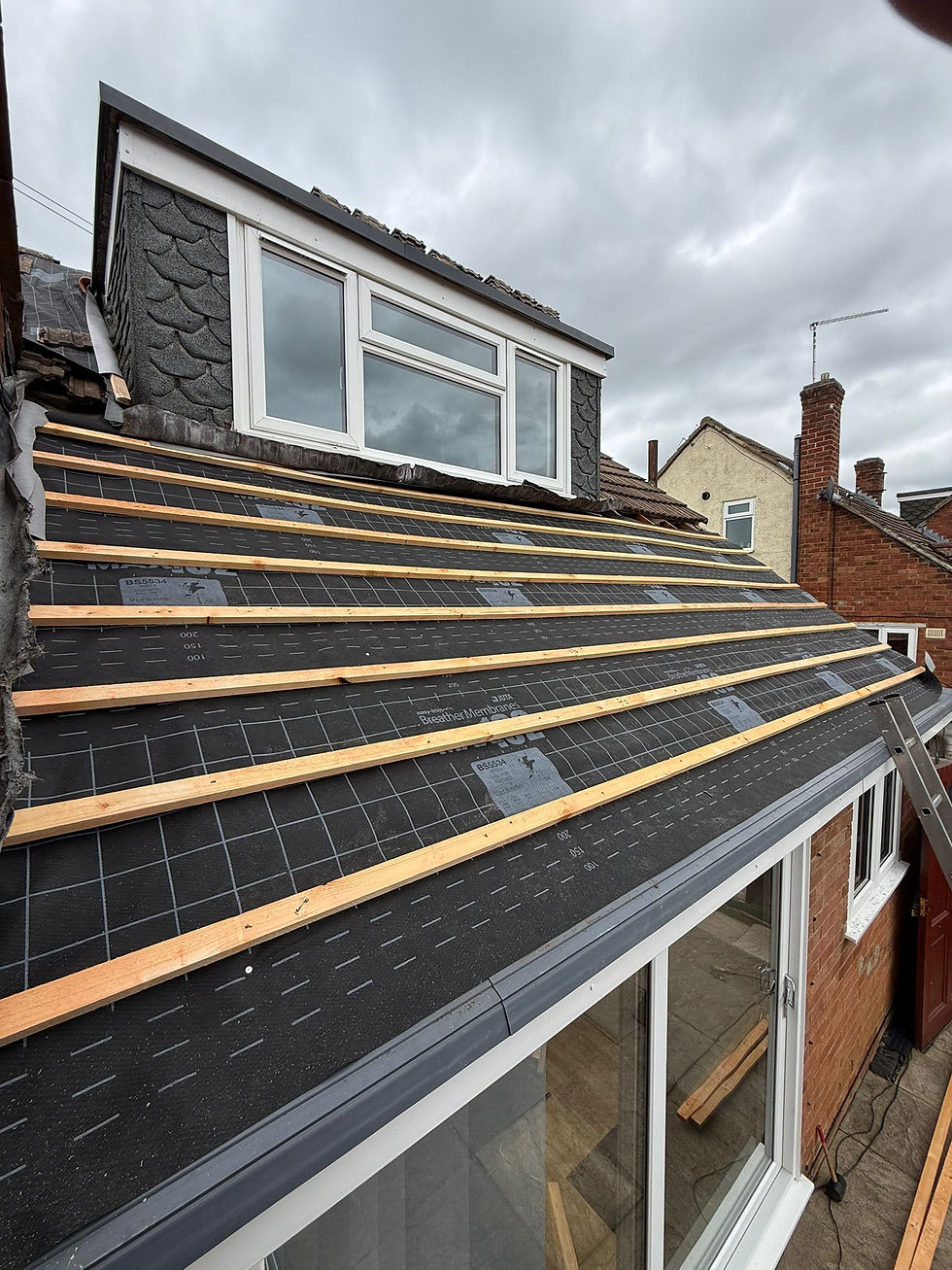 Grey slate roof tiles and metal flashing, shown on a cloudy day.