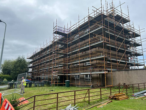 Large multi-storey residential building completely covered in scaffolding for commercial renovation work