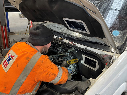 Mechanic in orange hi-vis jackets inspecting open engine bay of a commercial vehicle