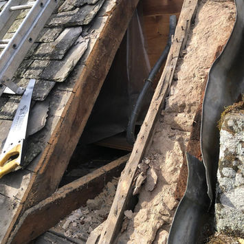 Damaged structural timber rafters and old insulation under a roof