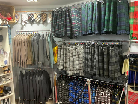 Retail shop interior with rows of traditional tartan kilts and formal jackets hanging neatly on clothing rails