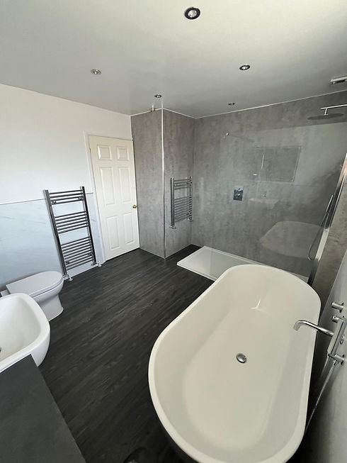 Oval freestanding bathtub next to a grey tile walk-in shower and wall-hung toilet