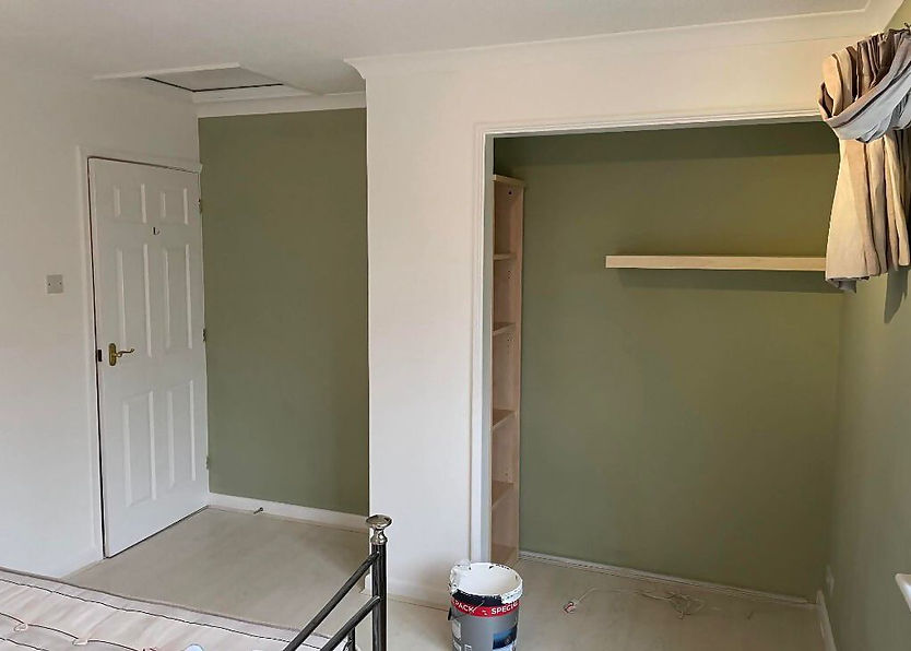 Empty room with pale green walls and two windows letting in natural light
