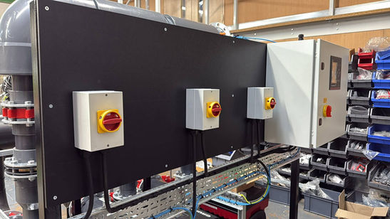 Row of red emergency stop buttons on a black wall-mounted control panel