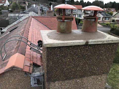 Pair of red clay chimney pots on a textured masonry stack