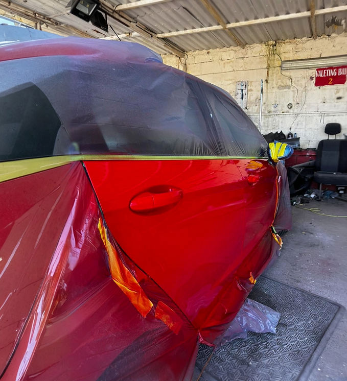 Red car undergoing professional repair service in modern automotive workshop
