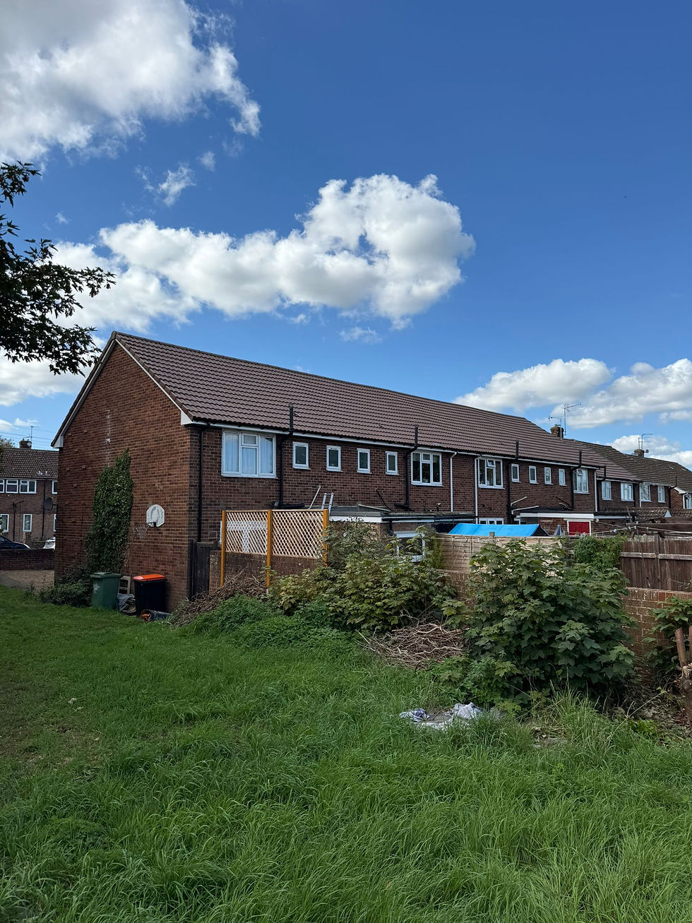 Red-brick house with a newly renovated tiled roof under a cloudy sky.
