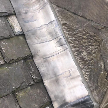 Lead valley flashing installed tightly against slate roof tiles