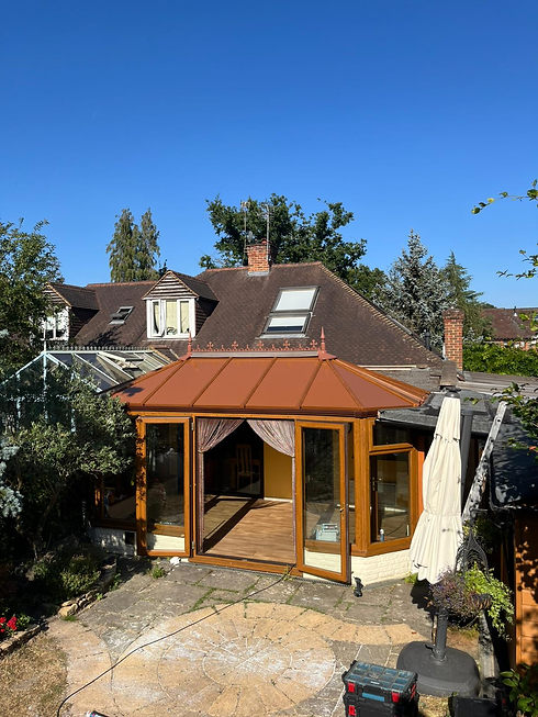 Wooden framed conservatory with tiled roof lit up in the evening