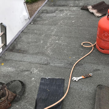 Flat roof surface with roofing tools and a red gas canister