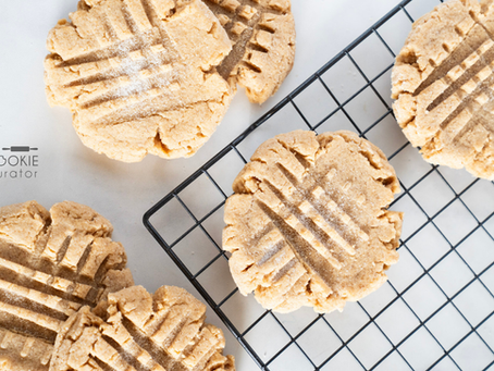 Soft classic peanut butter cookies with crisscross fork pattern, golden edges, and chewy centers on a parchment-lined baking sheet.