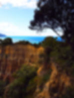 Orange formation of cathedral cliffs with blue ocean behind