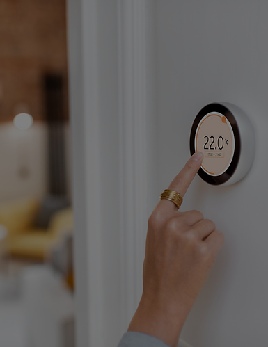 Hand adjusting a smart thermostat displaying 22 degrees in a modern home.