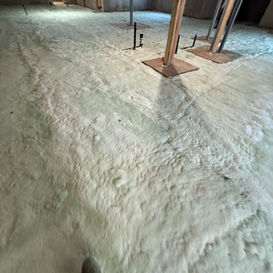 Basement with a foam-covered floor, wooden support beams, and concrete walls