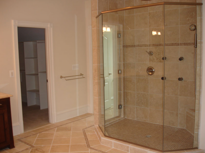 Large shower with bronze accents and slab tile