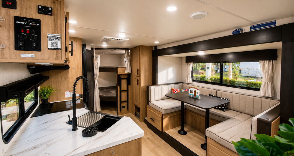 Open living and dining space with bunk beds and large windows inside the Sugar Wolf travel trailer