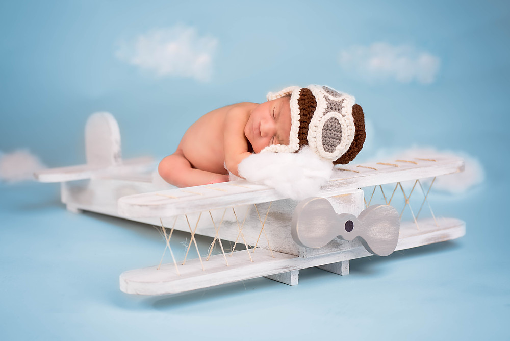 Great newborn picture in Overland Park of a baby pilot on her wooden airplane
