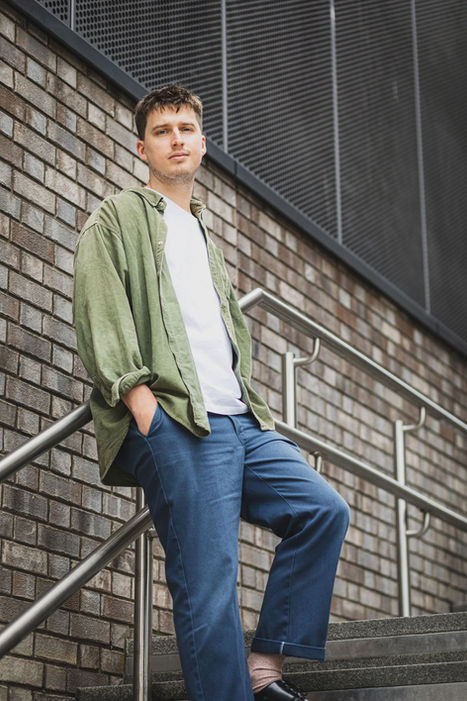 Modern portrait of man on steel stairs against brick wall, urban texture
