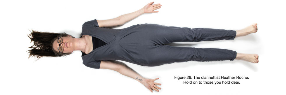 a woman in a grey jumpsuit is laying down with her arms outstretched
