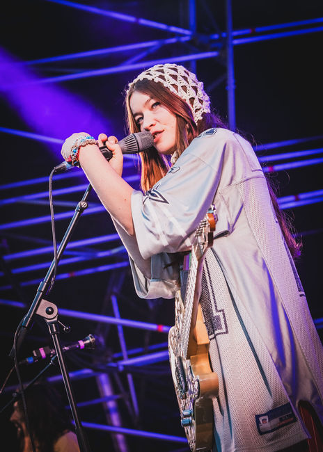 Vocalist gripping a microphone under bright white light.