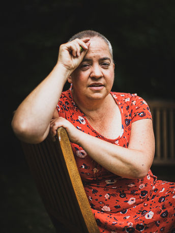 Person seated on a wooden bench outdoors, expressive pose, soft daylight.