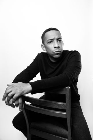 Flautist Eric Lamb in a dramatic black-and-white portrait, leaning on a chair with a strong and contemplative expression.