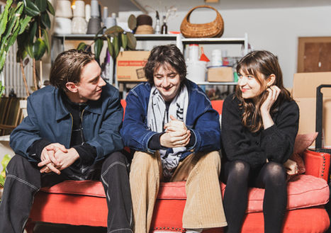 Trio chatting on a red sofa in a workshop space