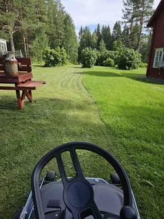 Åkgräsklippare som klipper en stor gräsmatta under sommaren i Västerbotten.