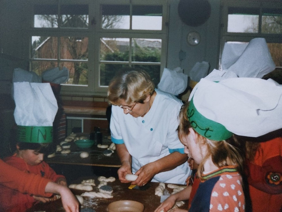 Communicantjes die met hulp van Wim, Nel en Pieter zelf enkele broodjes mogen maken. Van links naar rechts: Inge van Roij, Nel, en Liselot Kessels