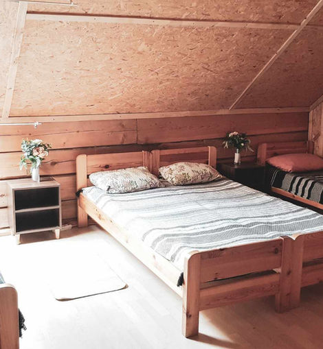 Mediniai lovų kambario interjeras, langas ir gėlės ant naktinių staliukų erdvėje.