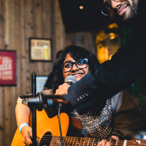 Girl playing the guitar and singing at a friend's sangeet